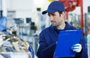 Specialist (auto control), an auto mechanic in a car service, checks the machine diagnostics. Concept: repair of machines, fault diagnosis, repair specialist, technical maintenance, on-board computer.