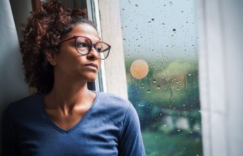 Portrait of pensive black woman standing beside window